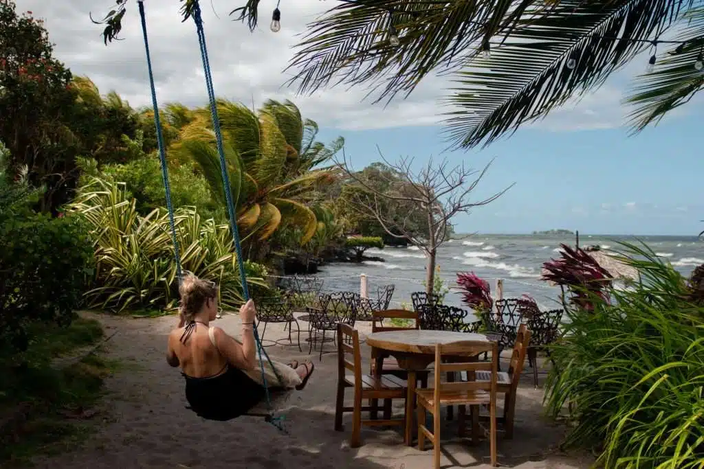 A woman swings beneath palm trees with views of crashing waves and lush greenery at Playa Mangos Beach on Ometepe Island. This laid-back coastal escape is ideal for anyone exploring things to do in Ometepe Nicaragua.