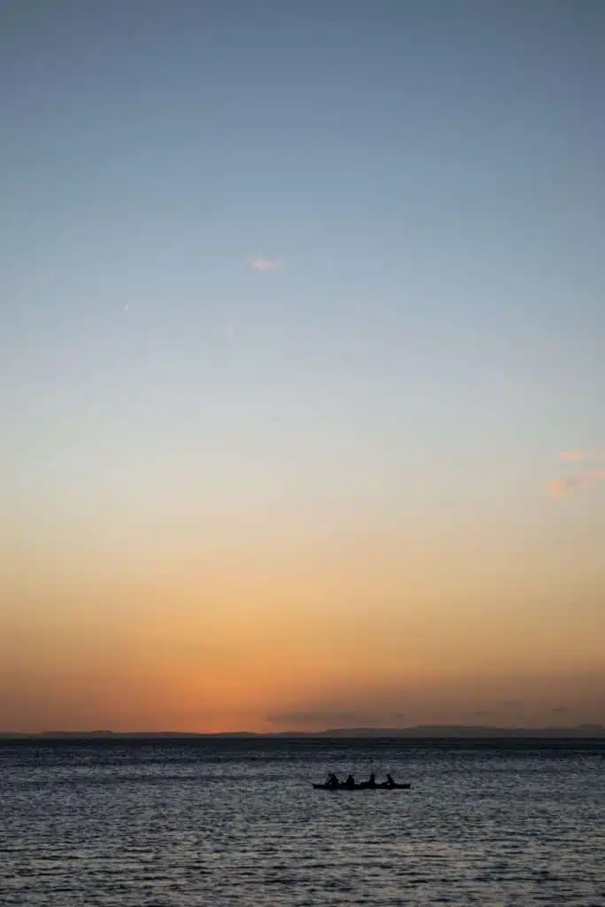 Silhouettes of people kayaking on Lake Nicaragua at sunset, with calm water and distant hills on the horizon. Kayaking Ometepe is one of the most peaceful and memorable things to do on Ometepe Island, perfect for any Ometepe travel guide.