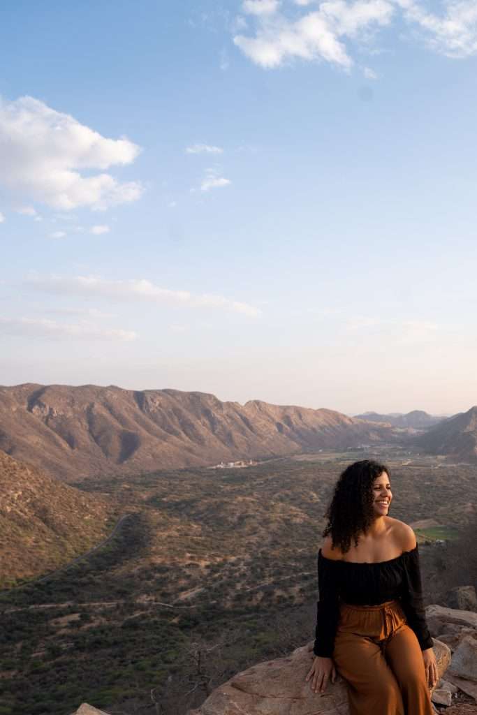 Woman sitting on a rock overlooking landscape view in Pushkar India - Backpacking in your 30s