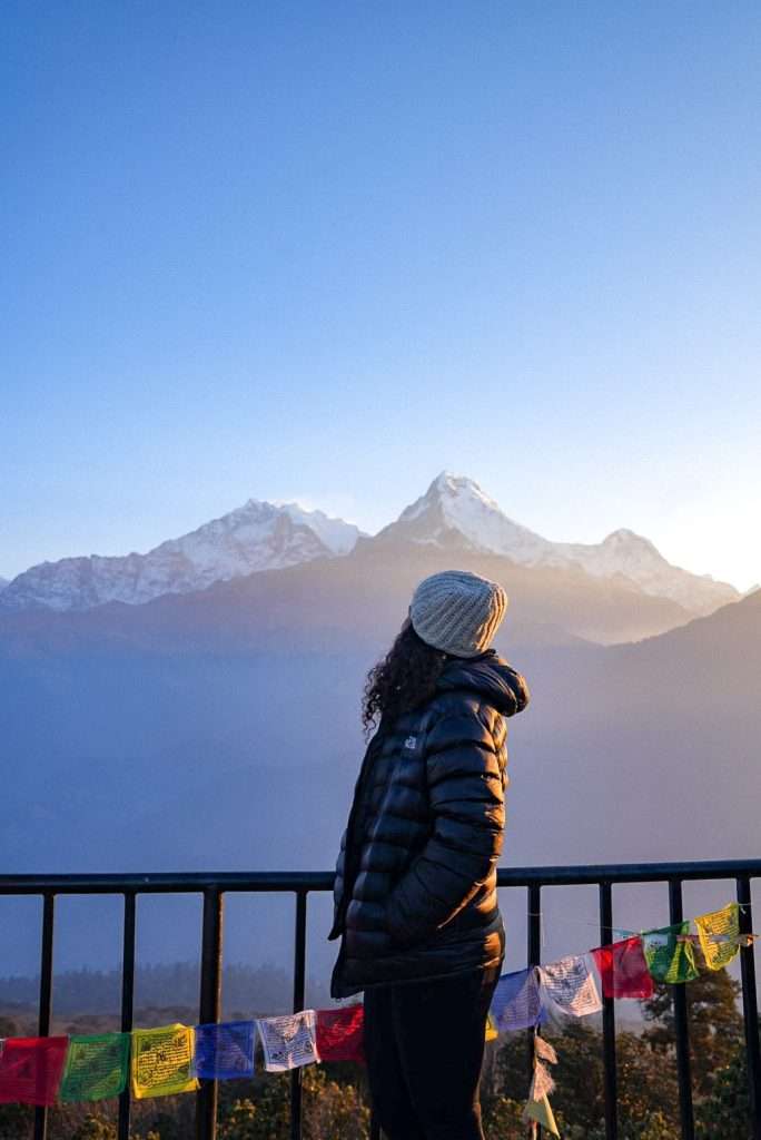 Woman standing in front of the Himalayas at sunrise - Backpacking in your 30s