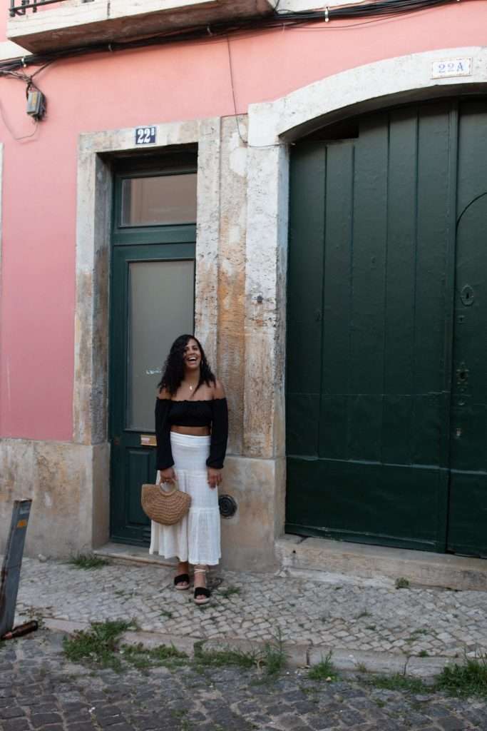 What to pack for a trip to Europe - Woman standing by colourful buildings in the streets of Lisbon