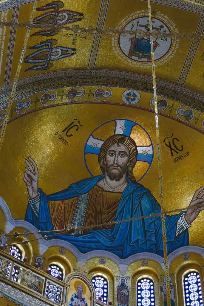 One day in Belgrade reveals a stunning mosaic of Jesus Christ on an ornate golden dome ceiling, adorned with intricate patterns and religious symbols. The artwork features halos and Greek letters, with decorative arches below, emphasizing its sacred setting.
